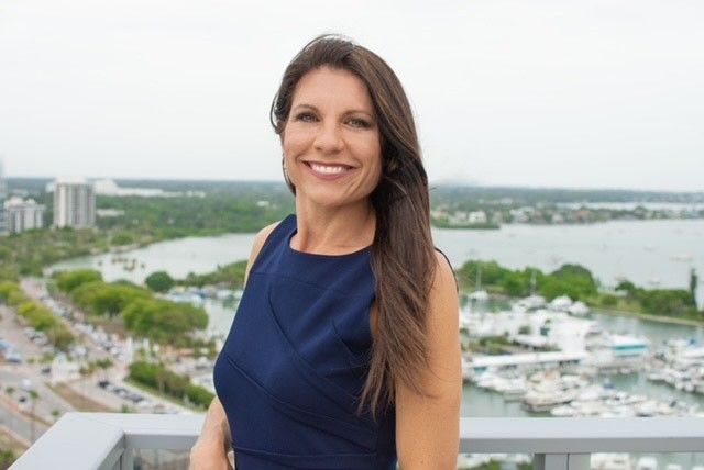 Smiling woman in blue dress on balcony.